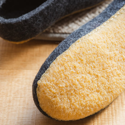 Close-up of a pair of slippers with a textured sole on a wooden surface